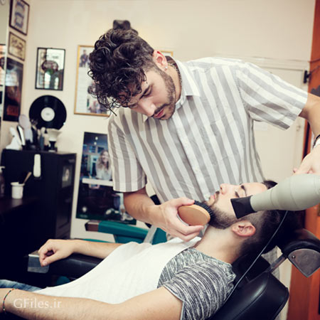 عکس با کیفیت از آرایشگر در حال اصلاح و سشوار ریش و صورت