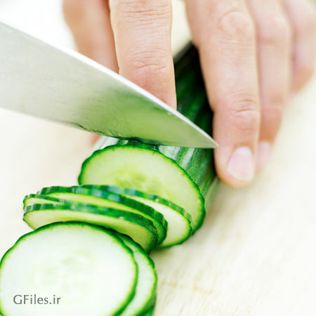 عکس چاقوی تیز در حال خرد کردن یک خیار سبز تازه