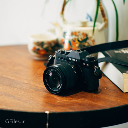 عکس میز چوبی با یک دوربین عکاسی بر روی آن